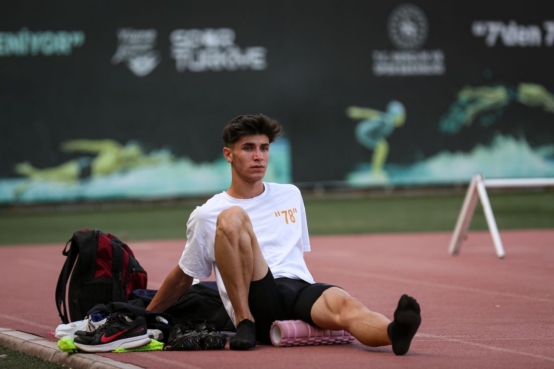 Athlete using a foam roller on a track after training