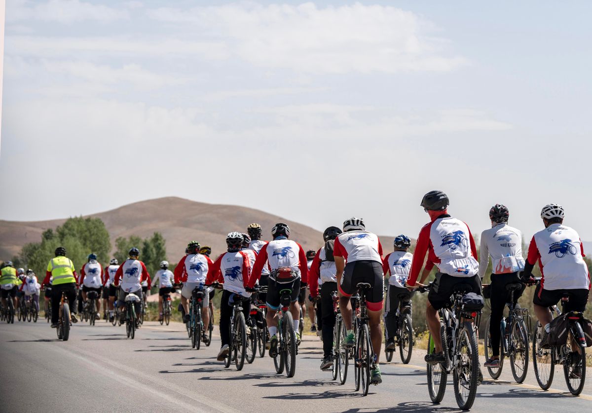 Group of cyclists riding together on a scenic road near hills